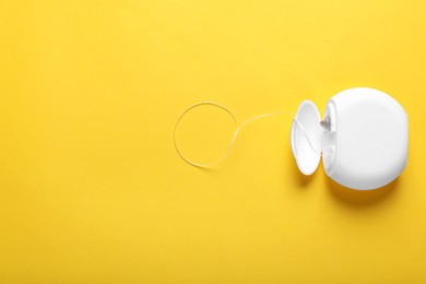 Photo of Container with dental floss on yellow background, top view. Space for text