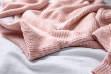 Pink warm sweater on white crumpled fabric, closeup