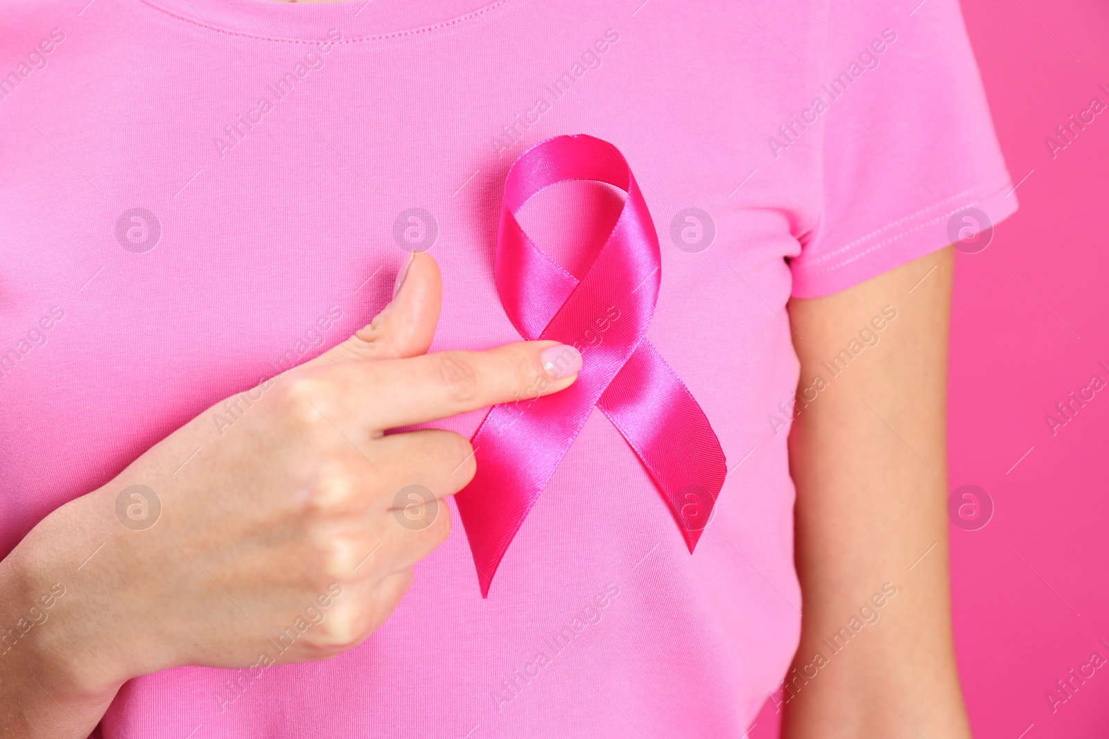 Photo of Woman with pink ribbon on color background, closeup. Breast cancer awareness