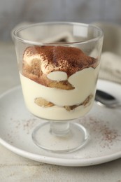 Photo of Delicious tiramisu in glass on light table