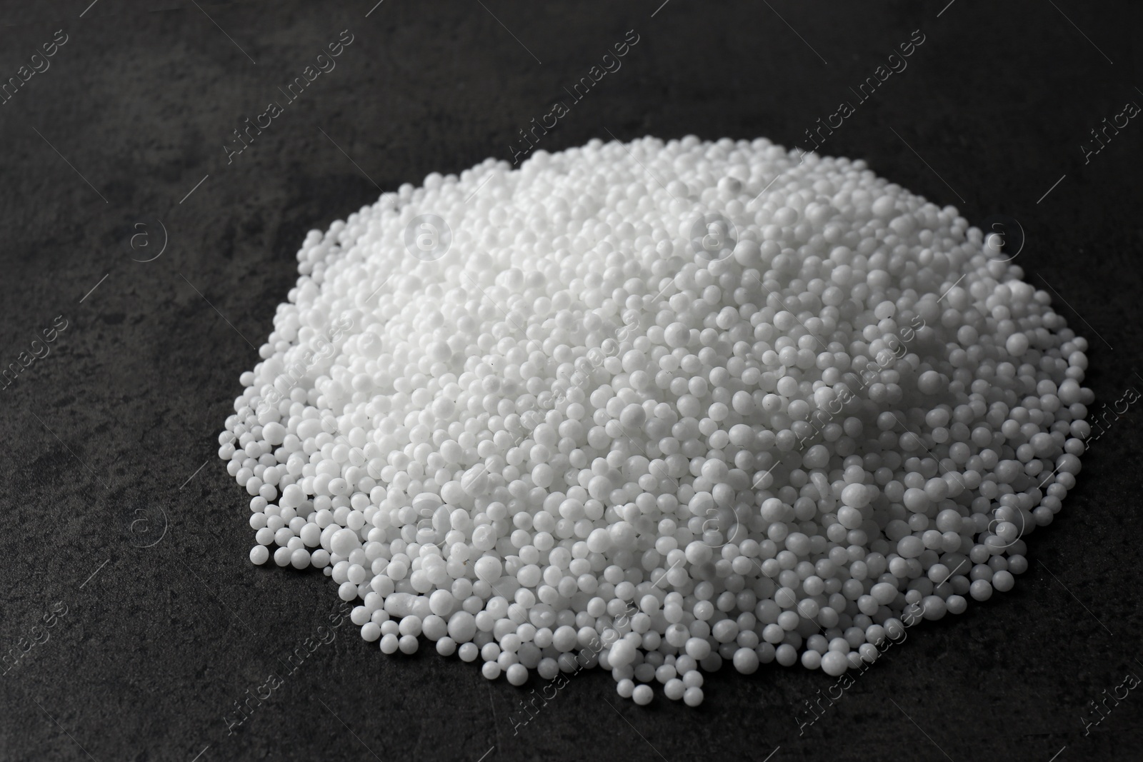 Photo of Pellets of ammonium nitrate on grey table. Mineral fertilizer