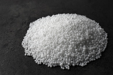 Pellets of ammonium nitrate on grey table. Mineral fertilizer