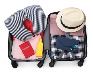 Photo of Soft travel pillow, hat, passports and other items in open suitcase isolated on white, top view