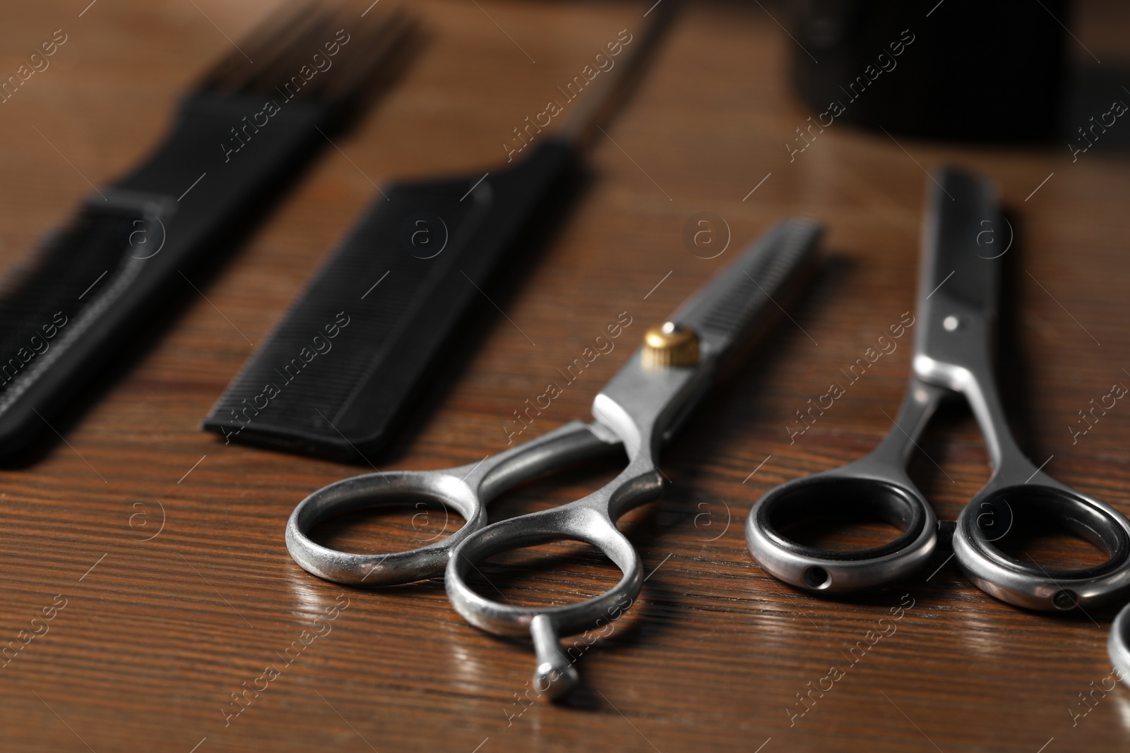 Photo of Hairdresser tools. Different scissors and combs on wooden table, closeup