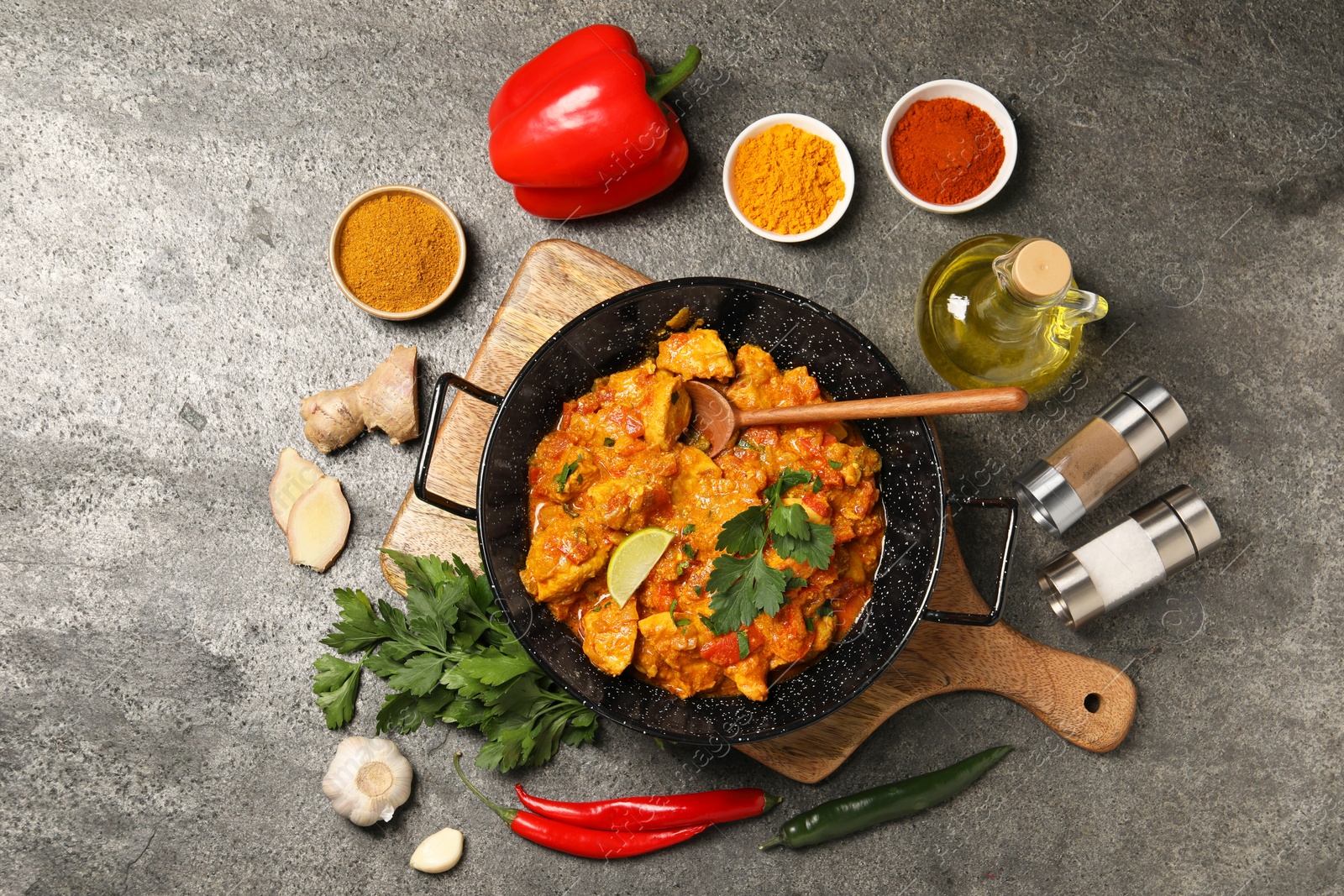 Photo of Delicious chicken curry and ingredients on grey table, flat lay