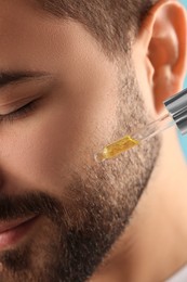 Man applying cosmetic serum onto face, closeup