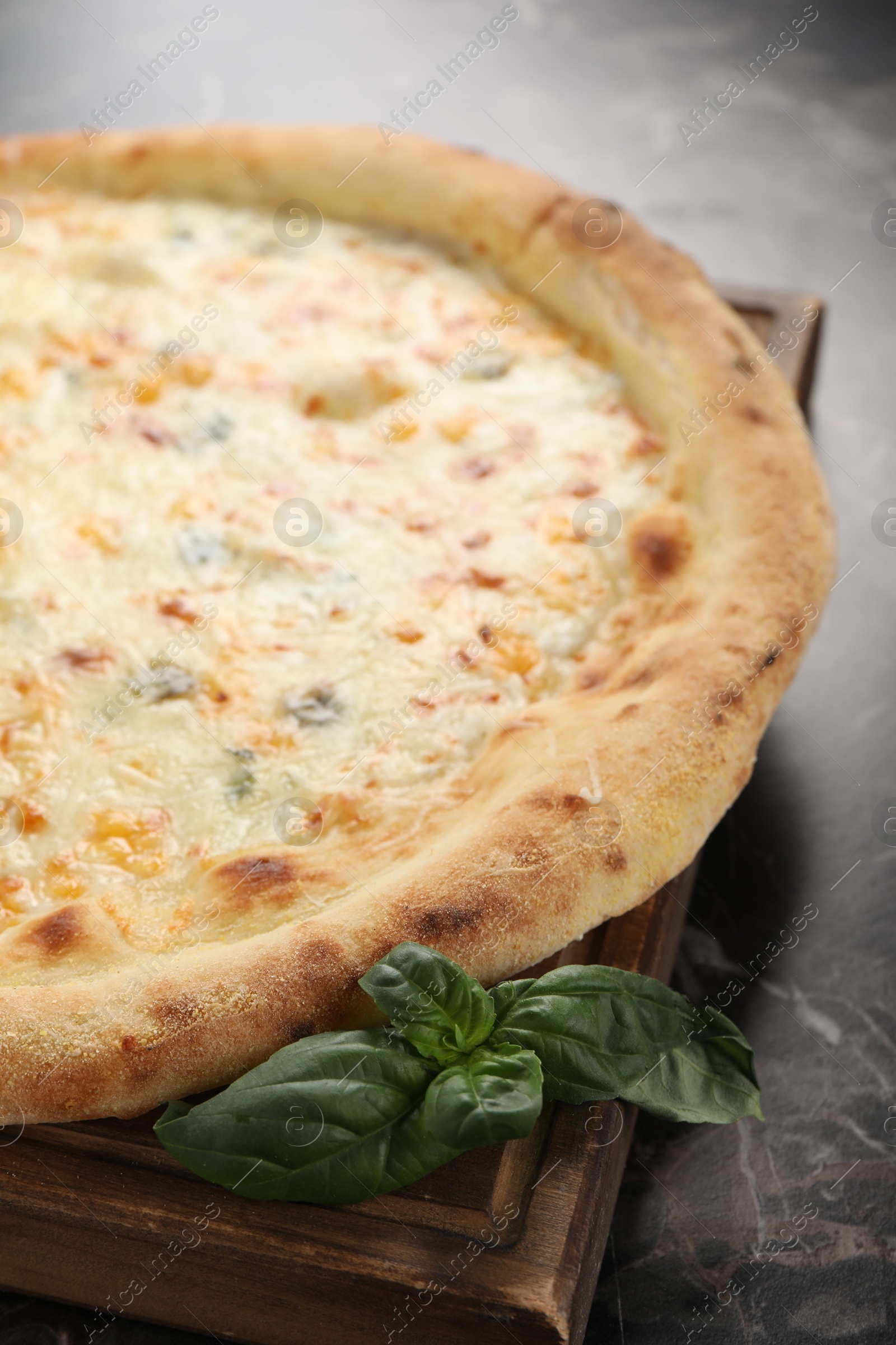 Photo of Delicious cheese pizza and basil on black marble table, closeup