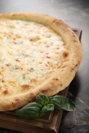 Delicious cheese pizza and basil on black marble table, closeup