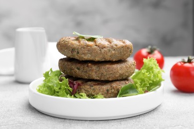 Photo of Delicious grilled vegan cutlets with lettuce on light grey table