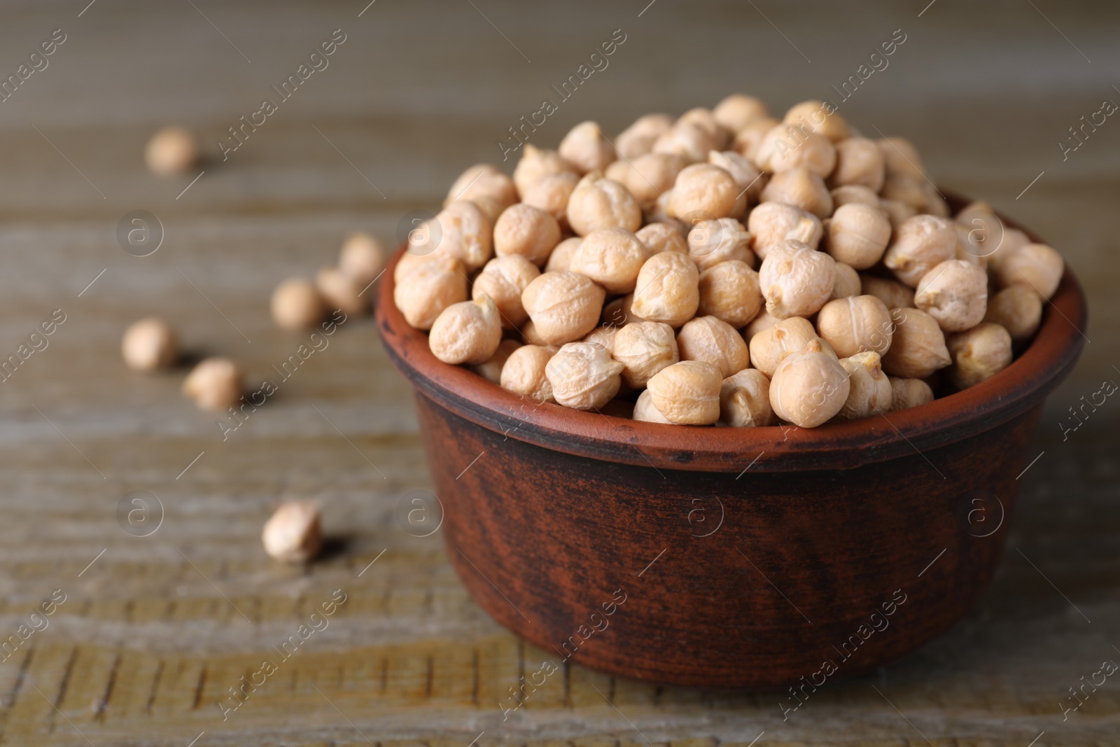 Photo of Chickpeas in bowl on wooden table, space for text