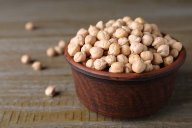 Photo of Chickpeas in bowl on wooden table, space for text