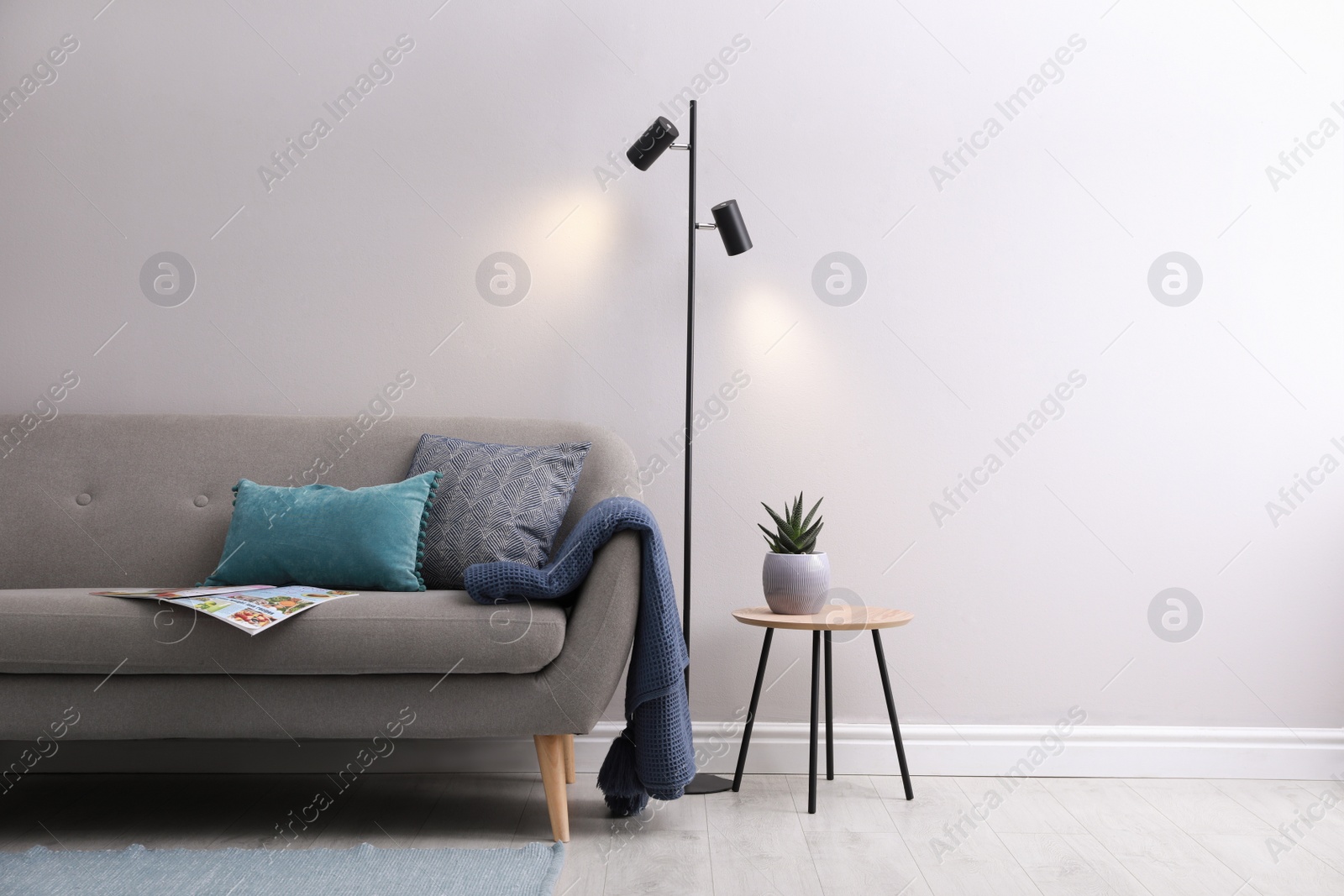 Photo of Stylish room living interior with comfortable sofa and lamp near white wall