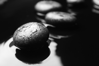 Wet spa stones on black background. Space for text