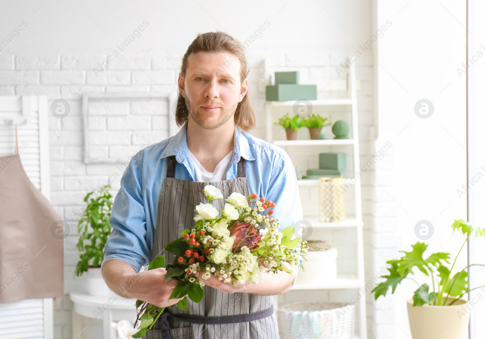 Photo of Male florist with beautiful bouquet at workplace