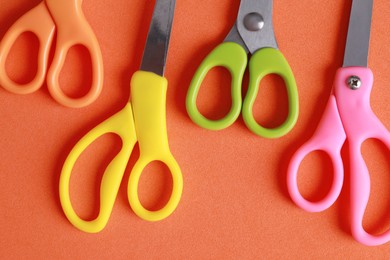 Photo of Different colorful scissors on coral background, flat lay
