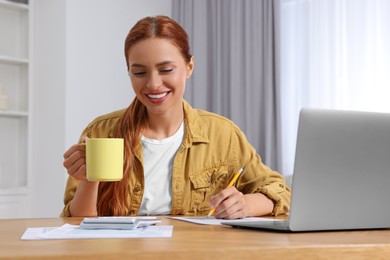 Woman calculating taxes at wooden table in room