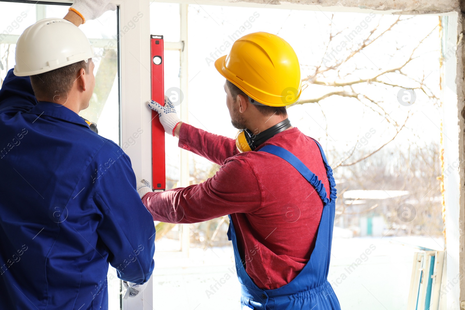 Photo of Workers using bubble level for installing window indoors