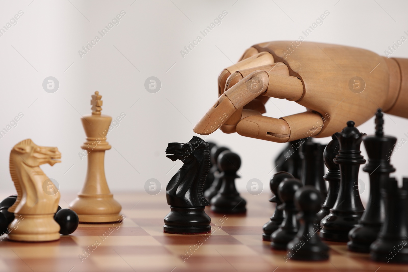 Photo of Robot moving chess piece on board against light background, closeup. Wooden hand representing artificial intelligence