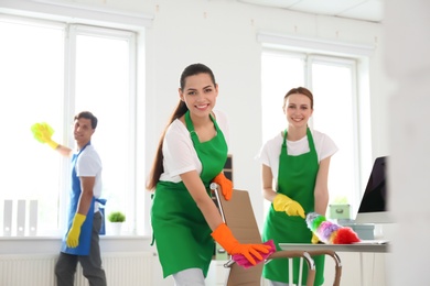 Team of professional janitors in uniform cleaning office