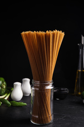 Uncooked buckwheat noodles and fresh ingredients on black table