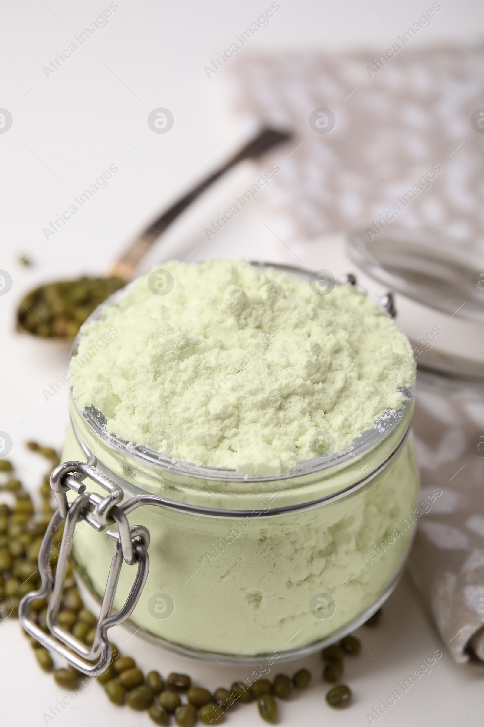 Photo of Glass jar of flour and mung beans on white table