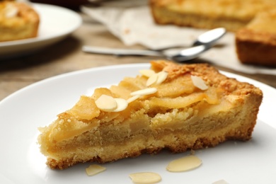 Photo of Piece of delicious sweet pear tart on table, closeup