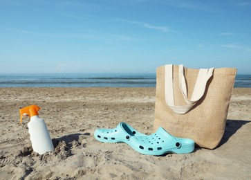 Bag, shoes and sun protection product on sandy beach