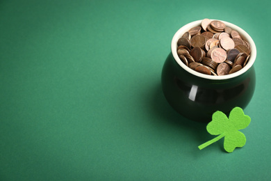 Photo of Pot of gold coins and clover on green background, space for text. St. Patrick's Day celebration