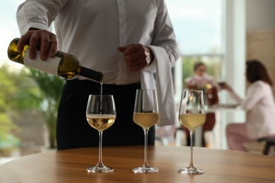 Photo of Waiter pouring wine into glass in restaurant, closeup