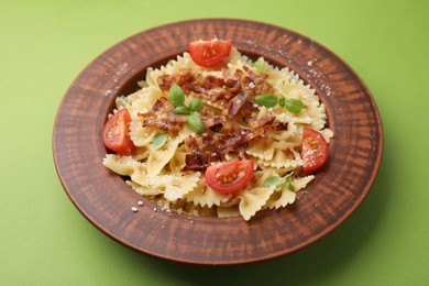 Photo of Tasty pasta with bacon, tomatoes and basil on light green table