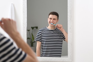 Photo of Man brushing his teeth with toothbrush near mirror in bathroom