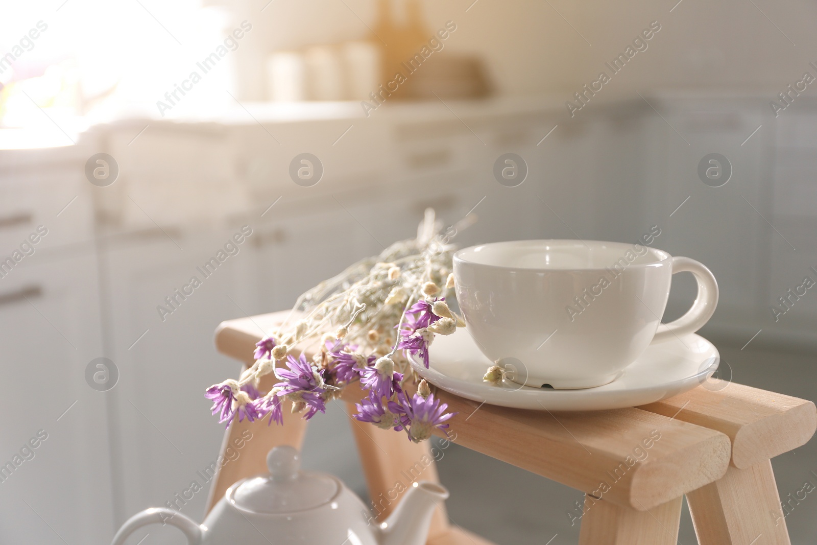 Photo of Decorative ladder with ceramic cup and flowers in kitchen, closeup. Idea for interior design