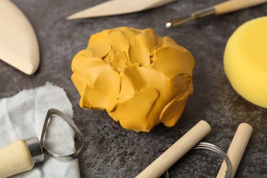 Photo of Clay and set of modeling tools on grey stone table, closeup