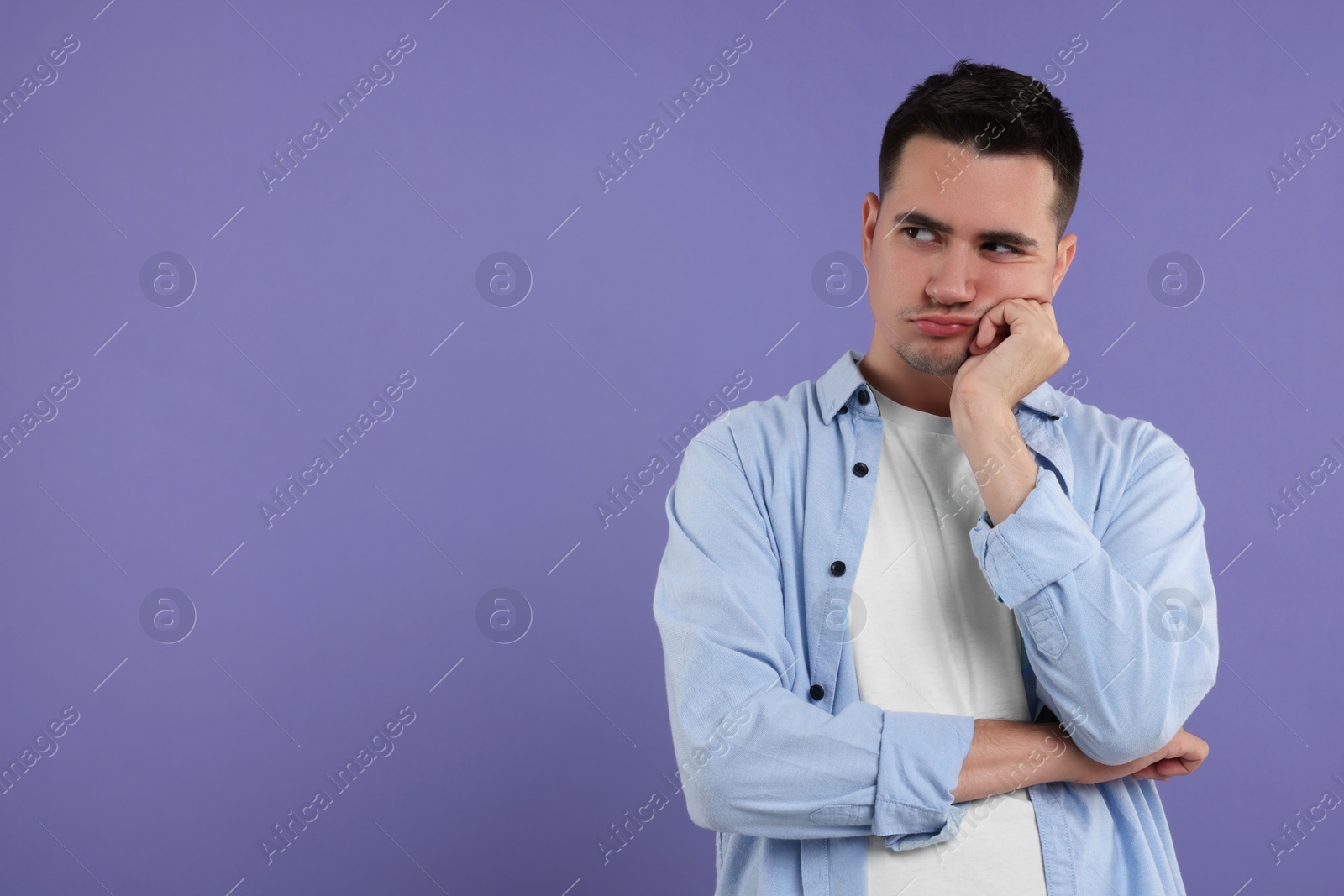 Photo of Resentful man on violet background, space for text