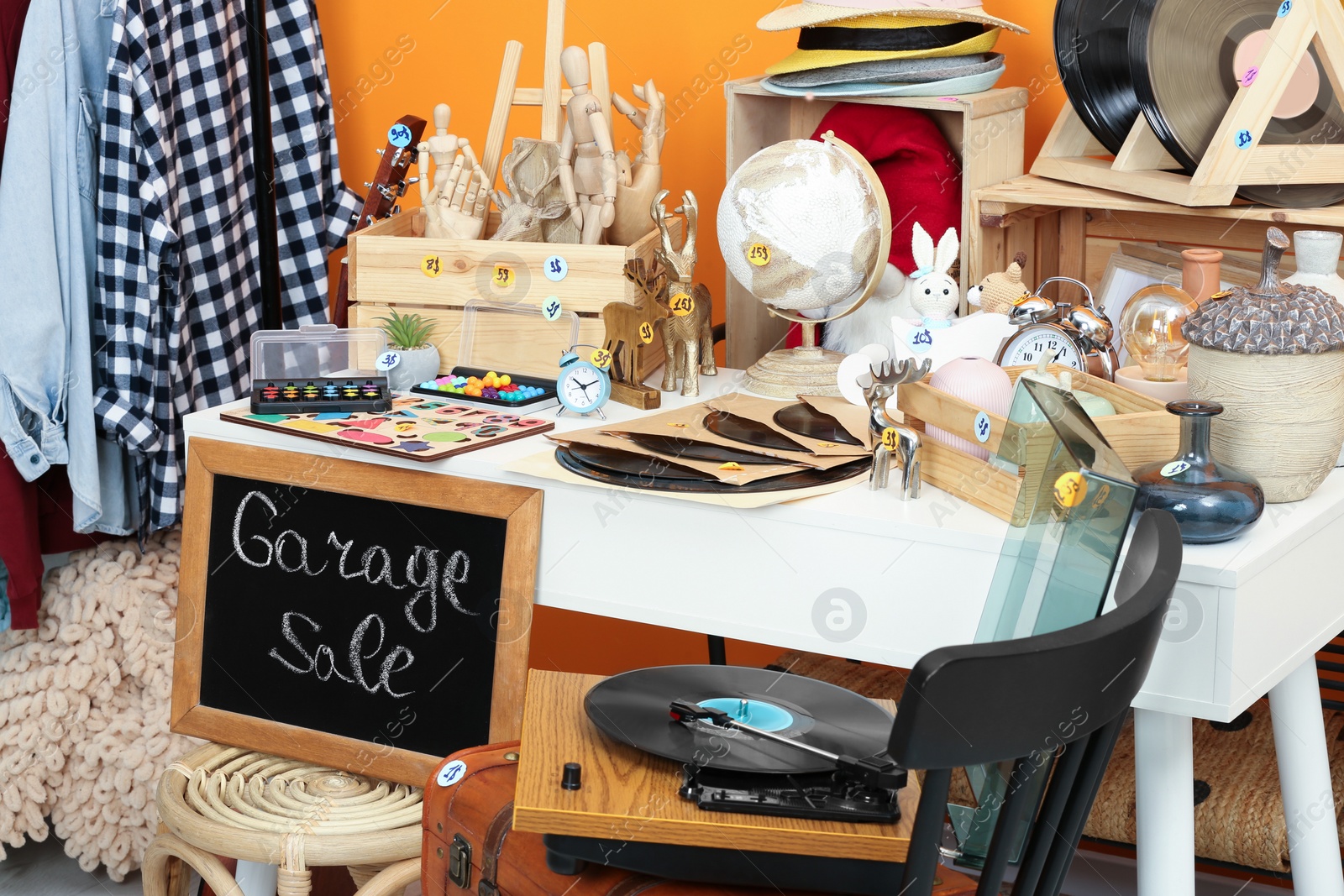 Photo of Sign Garage Sale written on blackboard near many different stuff