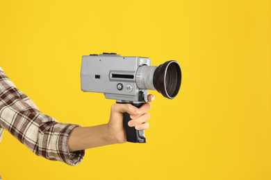 Woman with vintage video camera on yellow background, closeup of hand