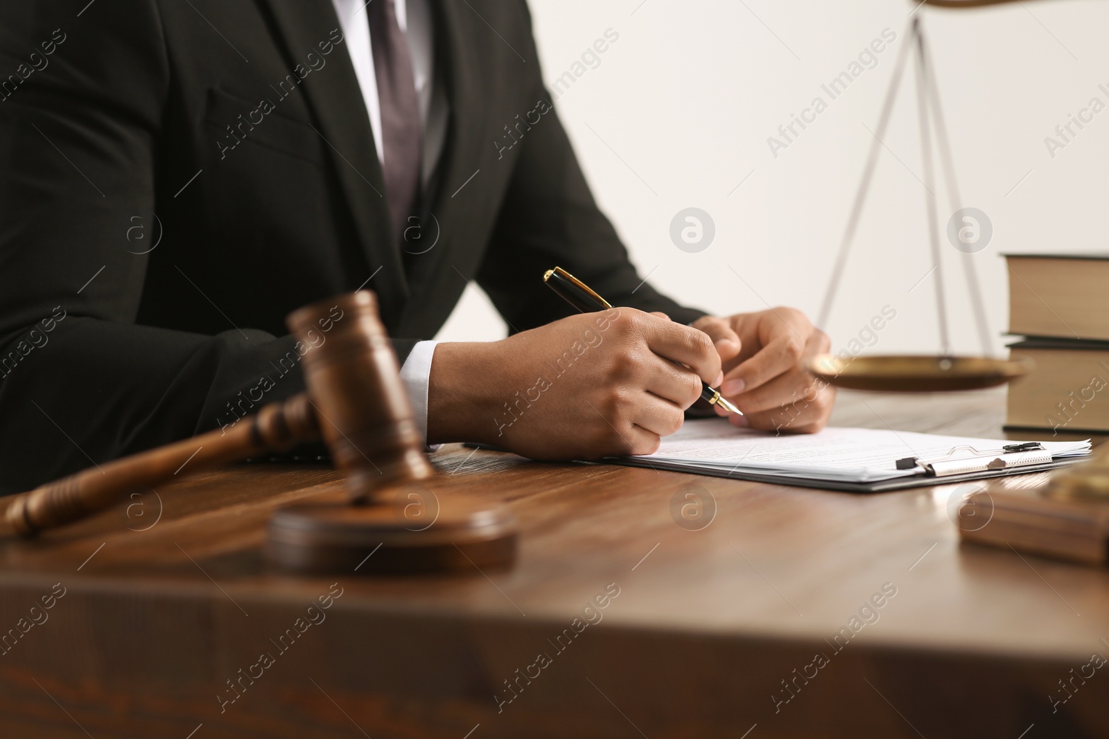 Photo of Law and justice. Closeup of judge working at wooden table near gavel