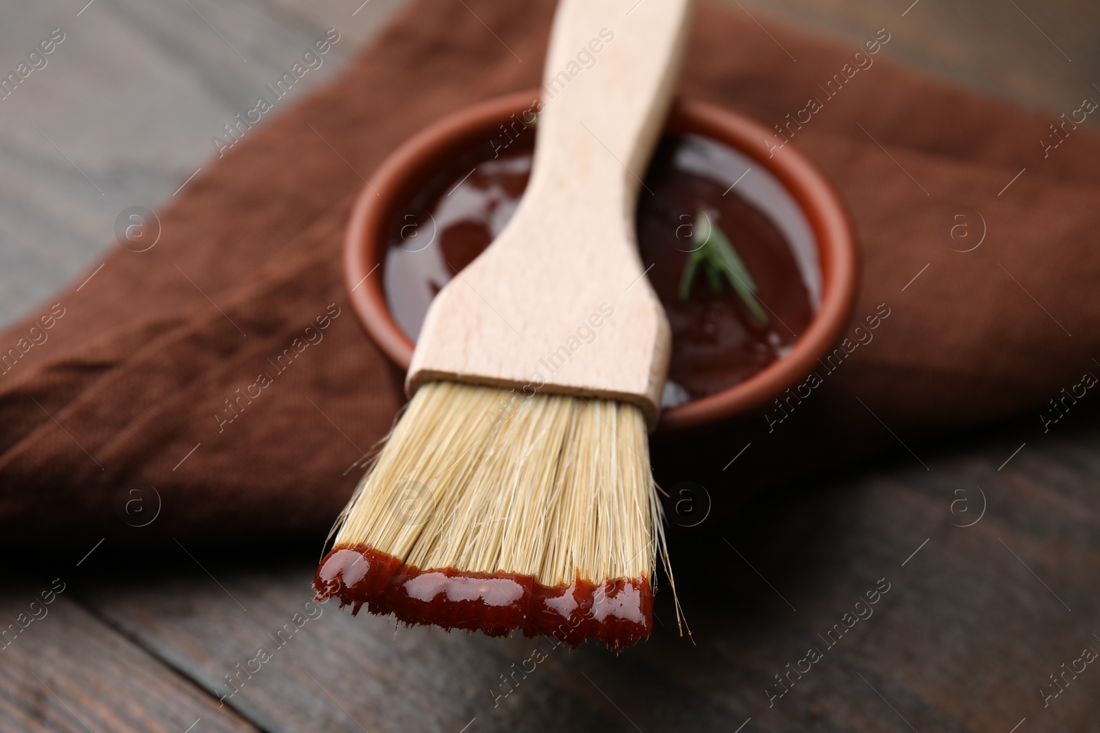 Photo of Marinade in bowl and basting brush on table, closeup
