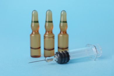 Photo of Disposable syringe with needle and ampules on light blue background