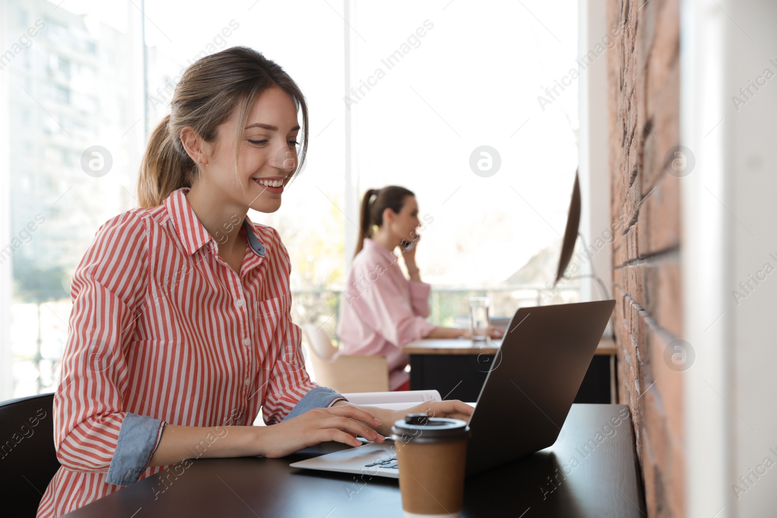 Photo of Young businesswoman using laptop at table in office