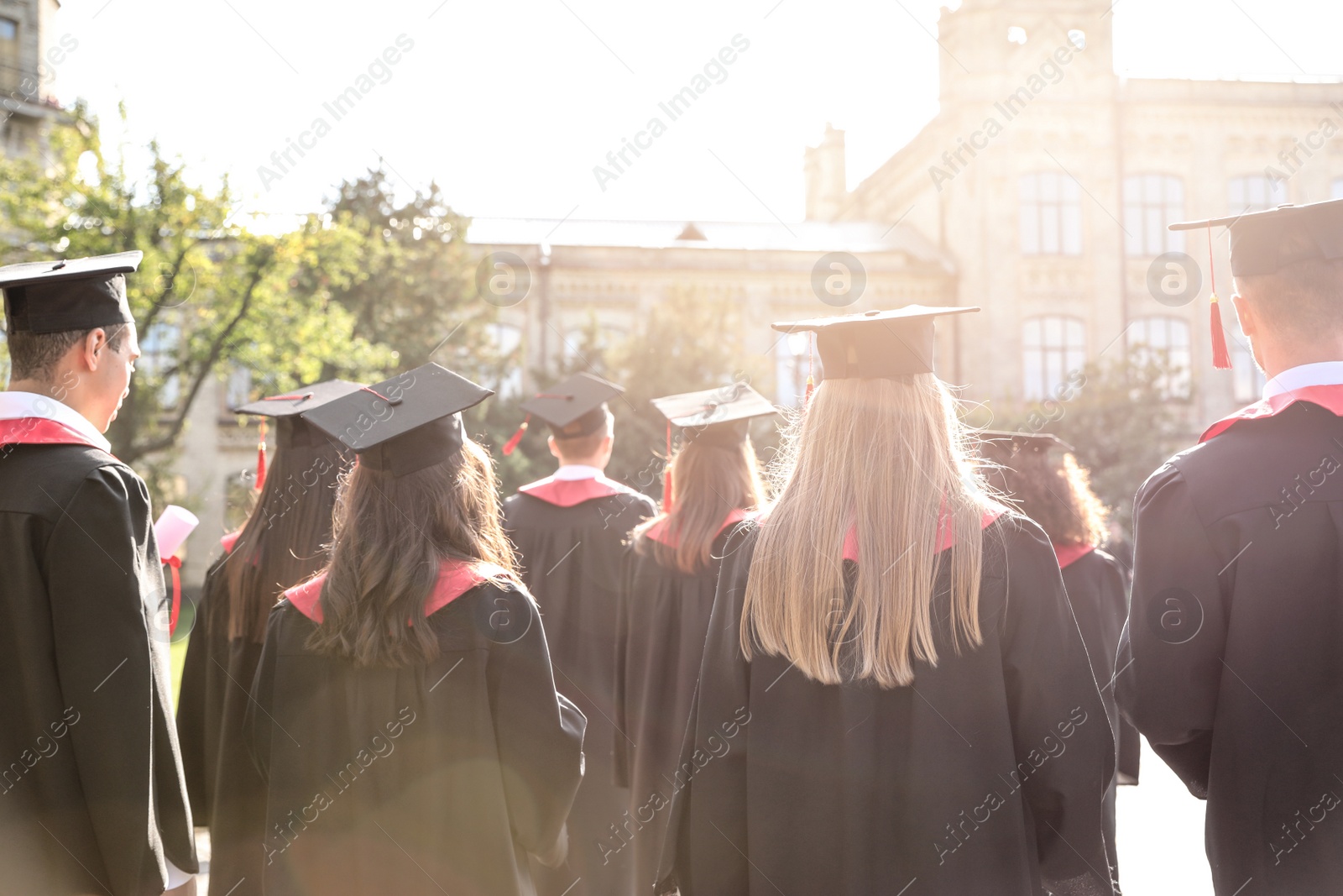 Photo of Group of students wearing academic caps and gowns outdoors. Graduation ceremony