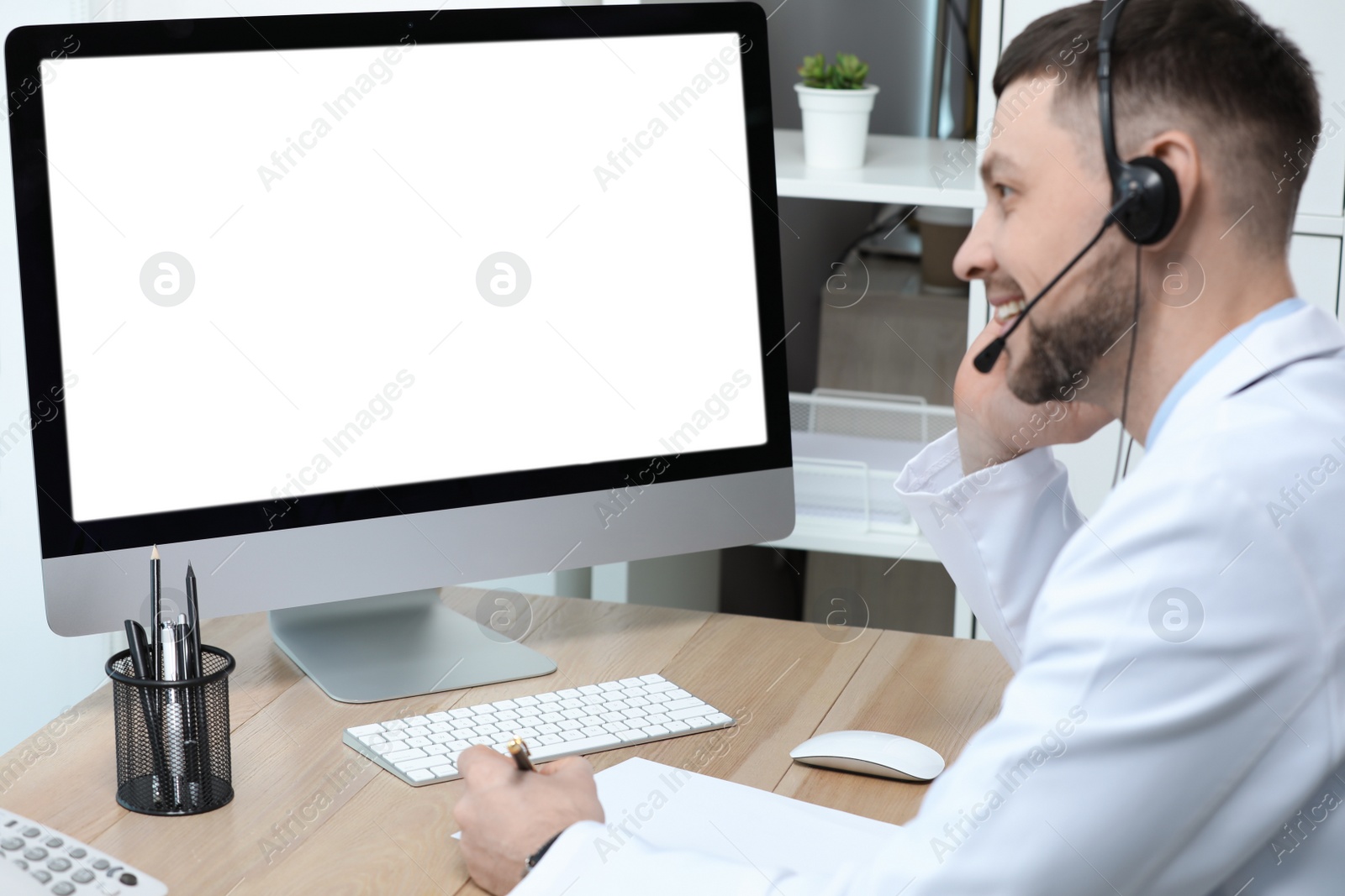 Photo of Doctor with headset consulting patient online at desk in clinic, space for text. Health service hotline