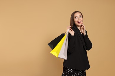 Photo of Stylish young woman with shopping bags on beige background, space for text