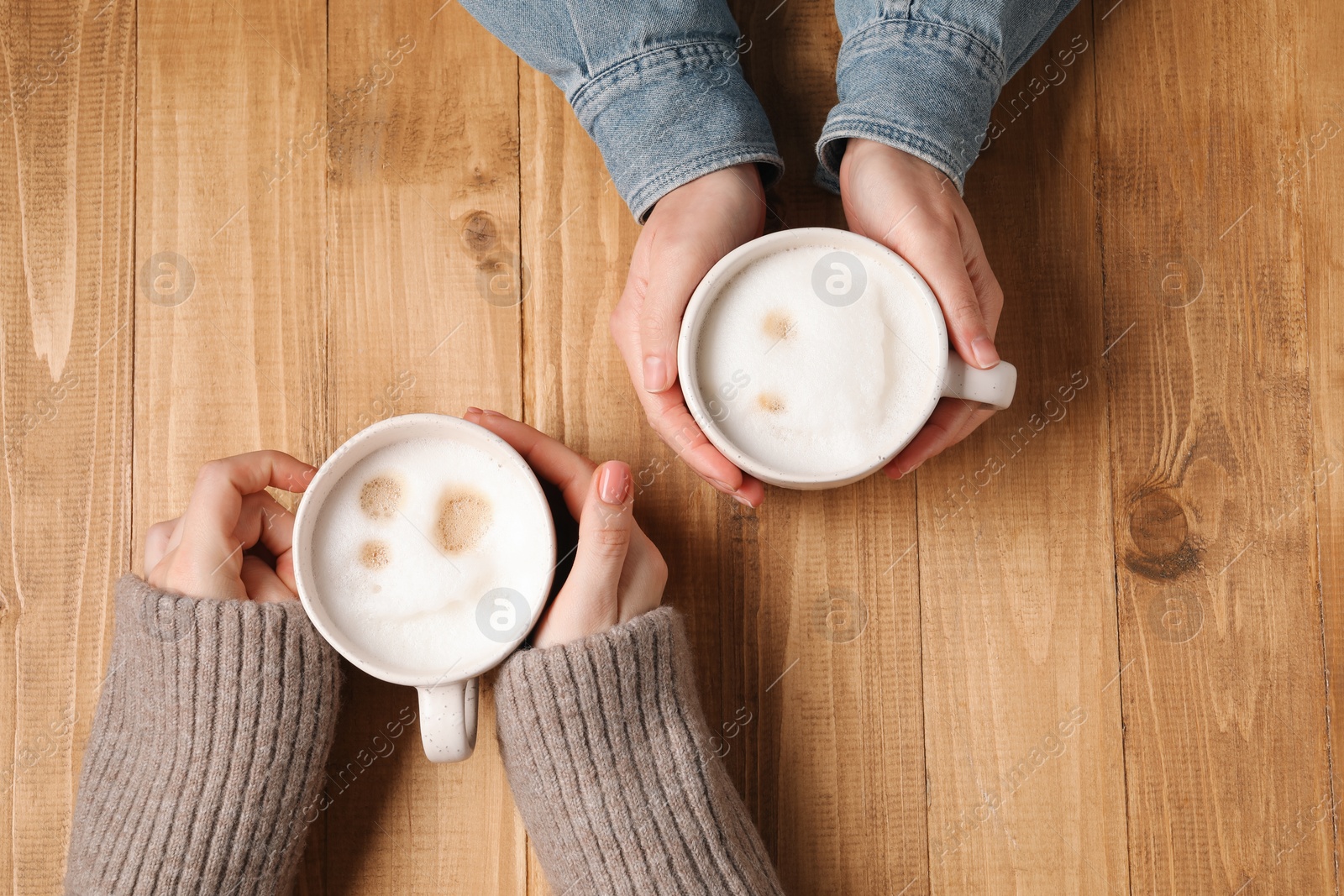 Photo of Women having coffee break at wooden table, top view