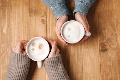 Photo of Women having coffee break at wooden table, top view