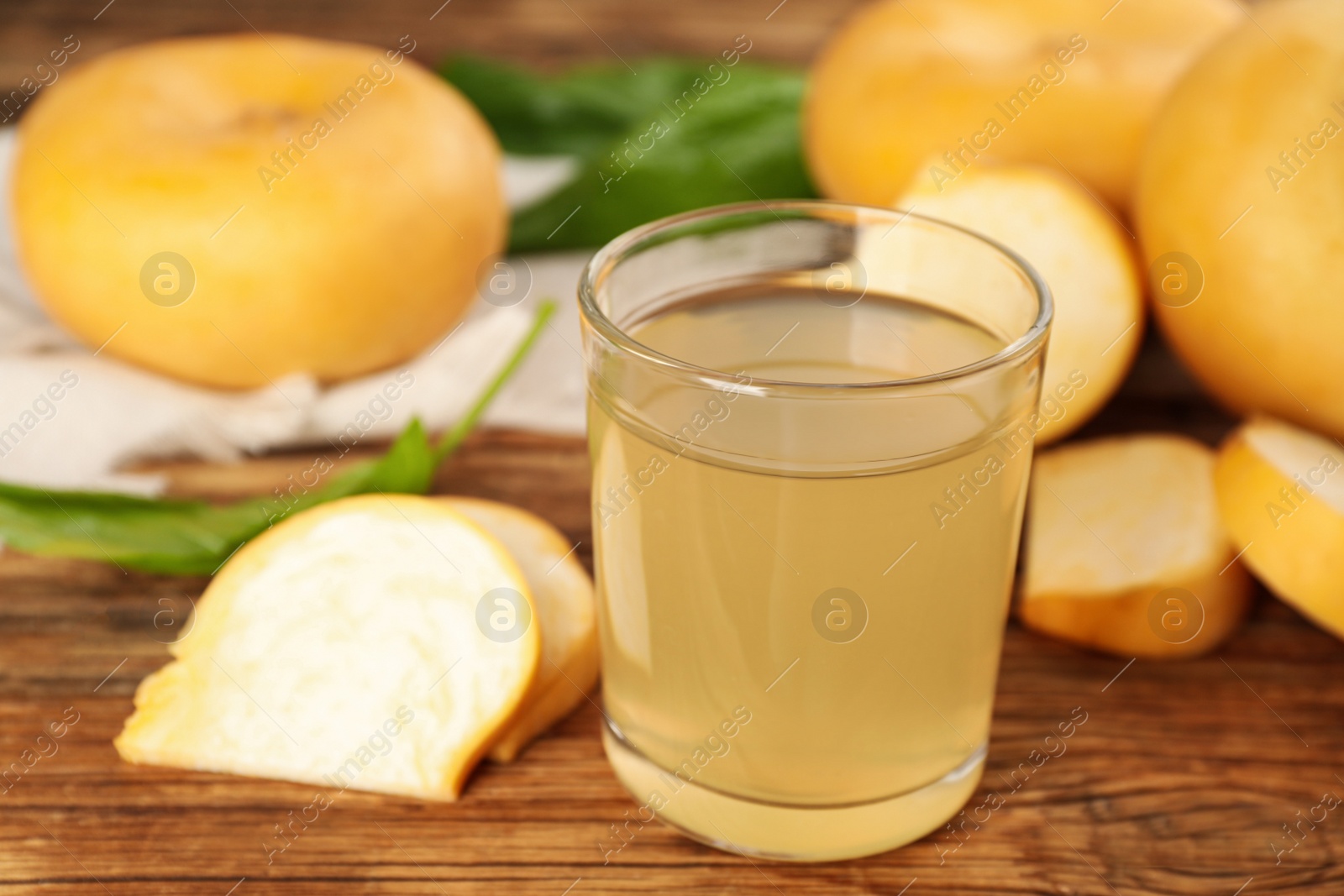 Photo of Glass of freshly made turnip juice on wooden table, closeup