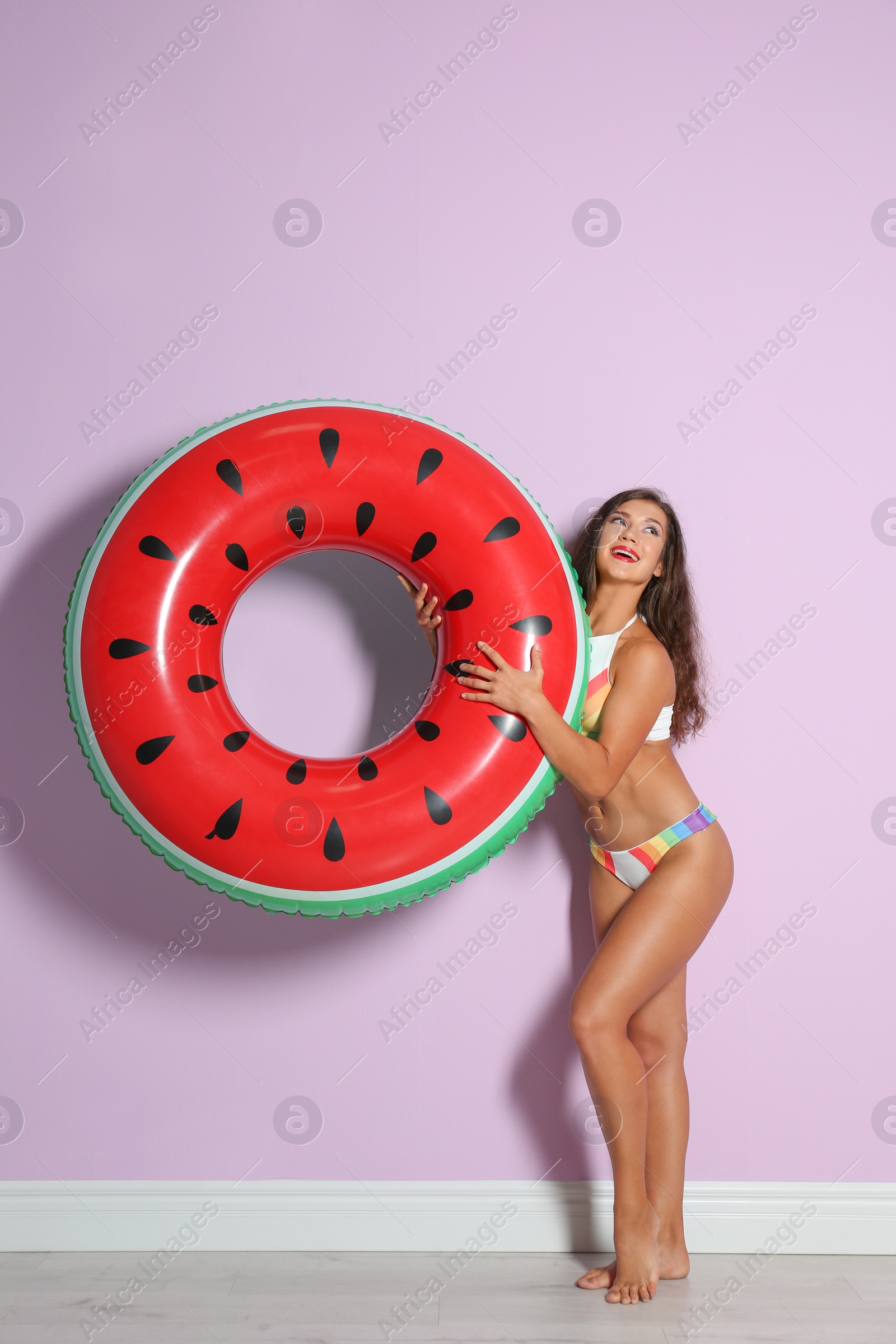 Photo of Beautiful young woman with inflatable ring near color wall