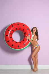 Beautiful young woman with inflatable ring near color wall