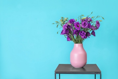 Photo of Beautiful bouquet of purple eustoma flowers in vase and space for text on color background