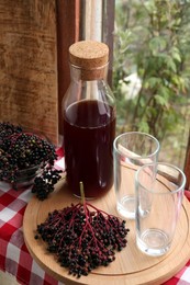 Photo of Elderberry drink and Sambucus berries on table near window